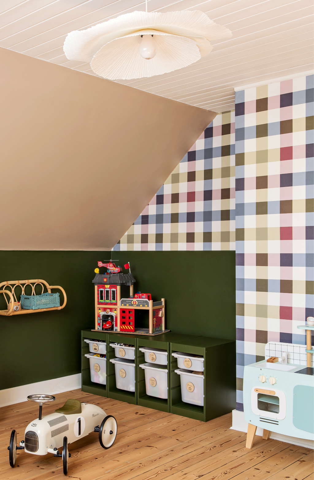 Papier peint Harold à grands carreaux croisés bleu, vert olive et vieux rose, posé sur le mur sous pente d'une salle de jeux pour enfants.