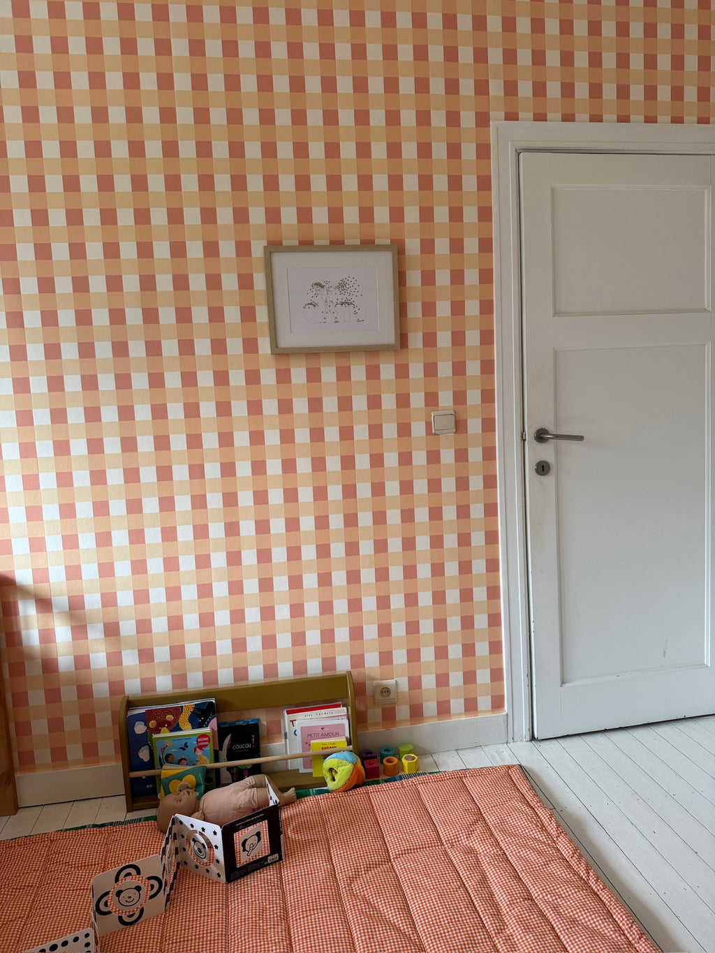 Papier peint à carreaux vichy orange et blanc modèle Jim dans une chambre d'enfant avec décoration.