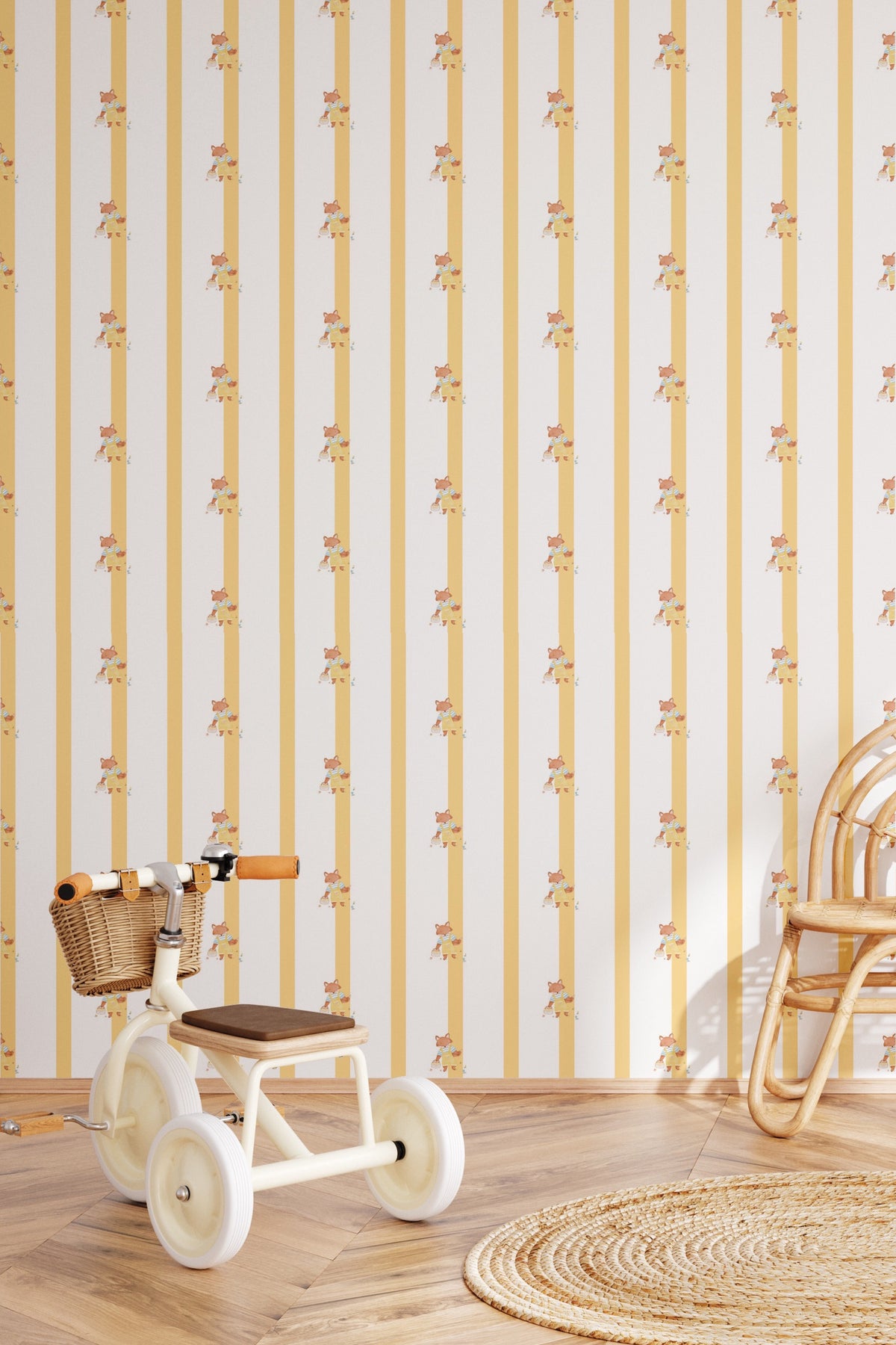 Papier peint Joy à rayures jaunes et illustrations de petits renards, posé dans une chambre d'enfant avec un tricycle vintage blanc, une chaise en rotin et un tapis rond en jute.