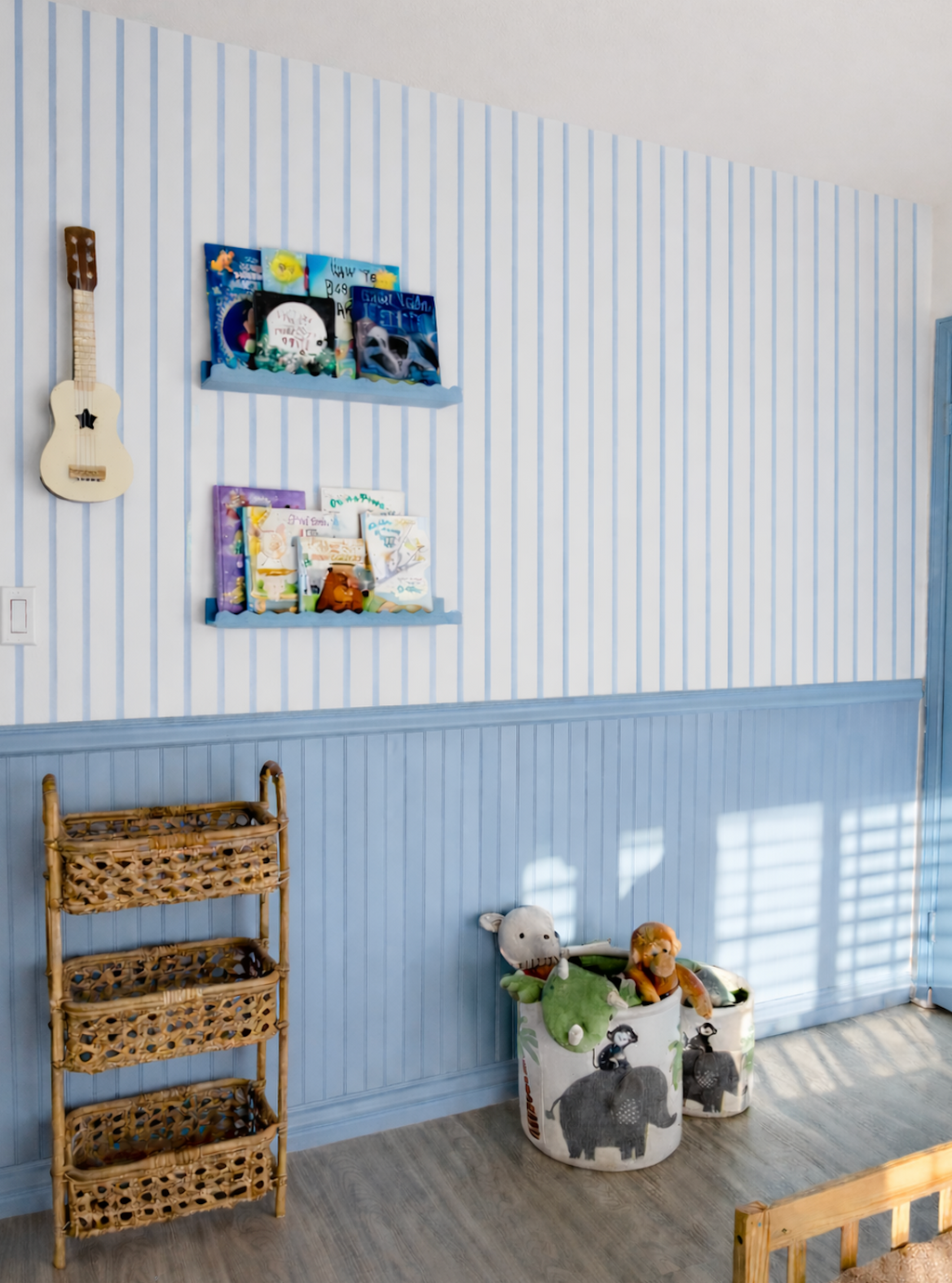 Papier peint Marine à rayures bleues au-dessus d'un soubassement bleu, avec étagères de livres, ukulélé et paniers de rangement.