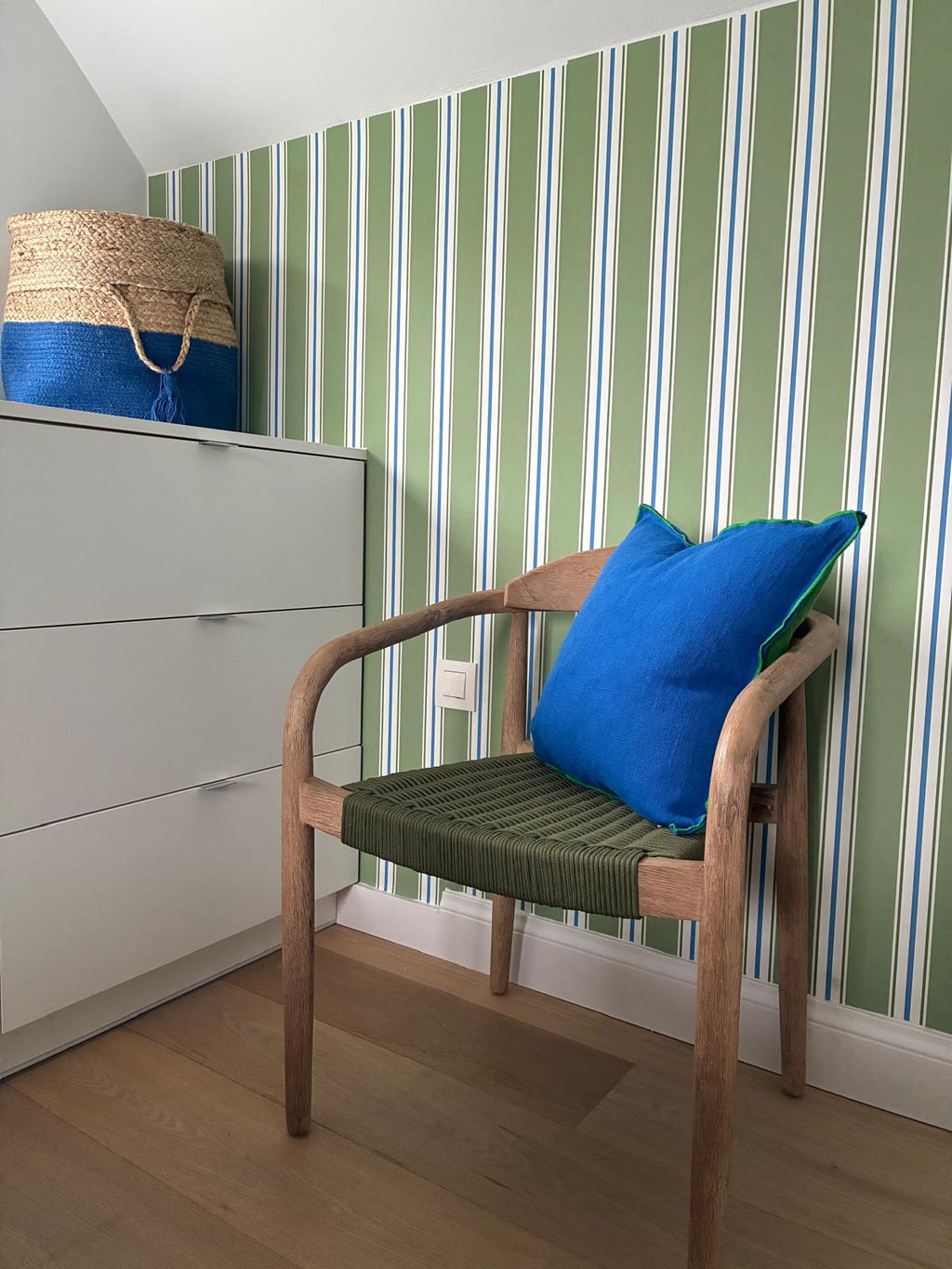 Papier peint rayures vertes et blanches et bleus chambre enfant posé dans une pièce avec chaise en bois